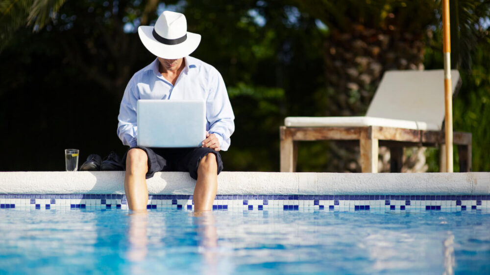 company-retreat-person-sits-working-by-pool