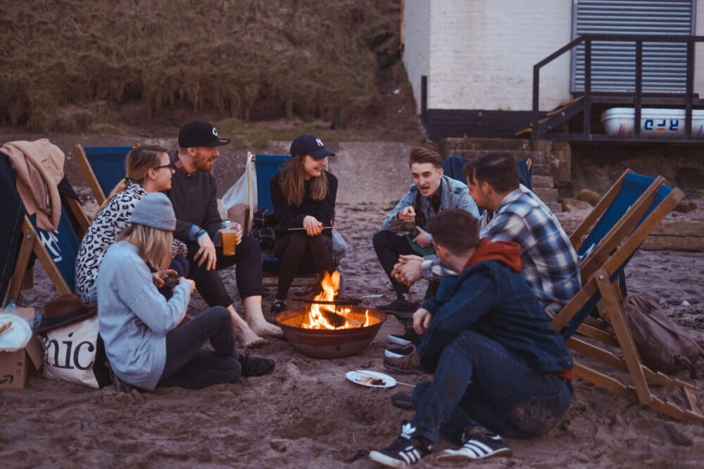 team-building-activities-for-work_flok_people-sitting-around-a-fire-at-the-beach