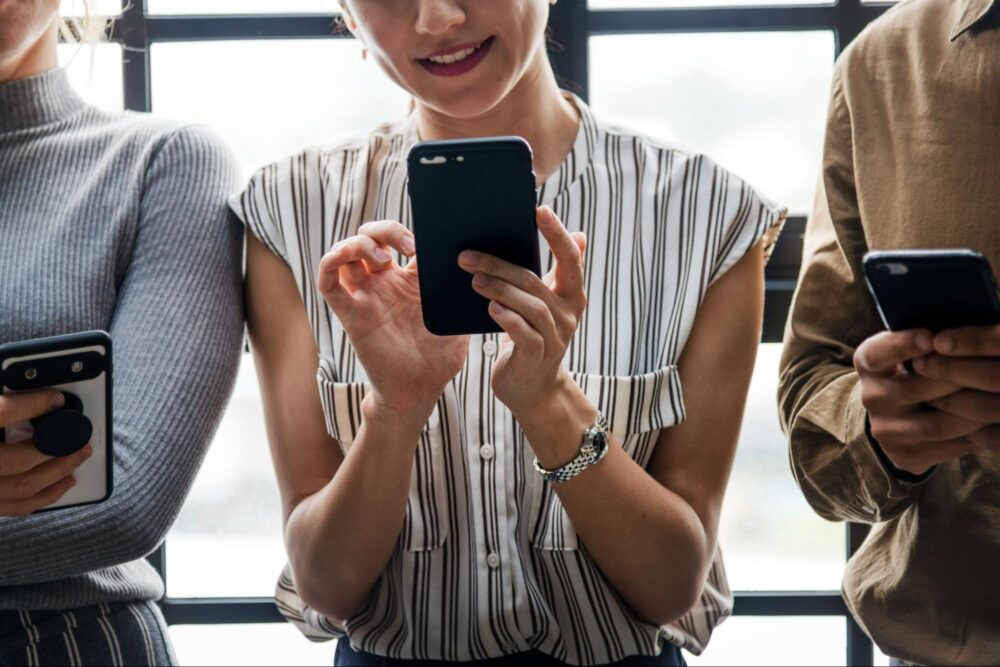 Woman holding a phone while smiling. Depiction of benefits of SMS Blast services